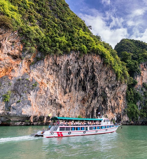 Projects Luxury cruise boat touring scenic tropical limestone cliffs and clear waters.