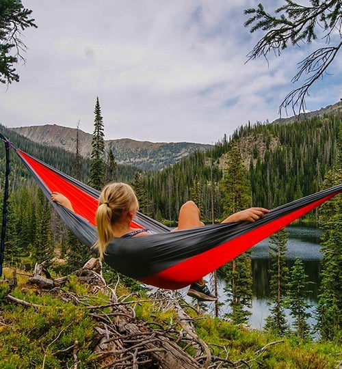 Projects * "A person relaxing in a hanging hammock between trees while camping in a dark forest setting."