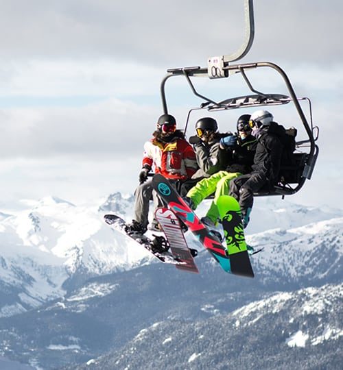 Projects : "Skiers and snowboarders riding a chairlift high above a snow-covered mountain resort."