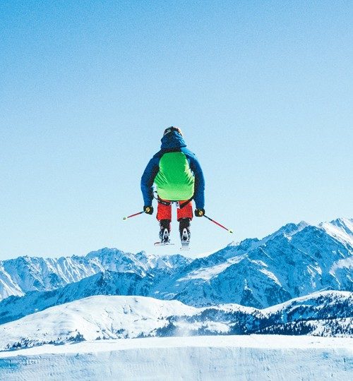 Projects * A snowboarder in bright gear carving down a wide, scenic snowfield on a clear winter day."